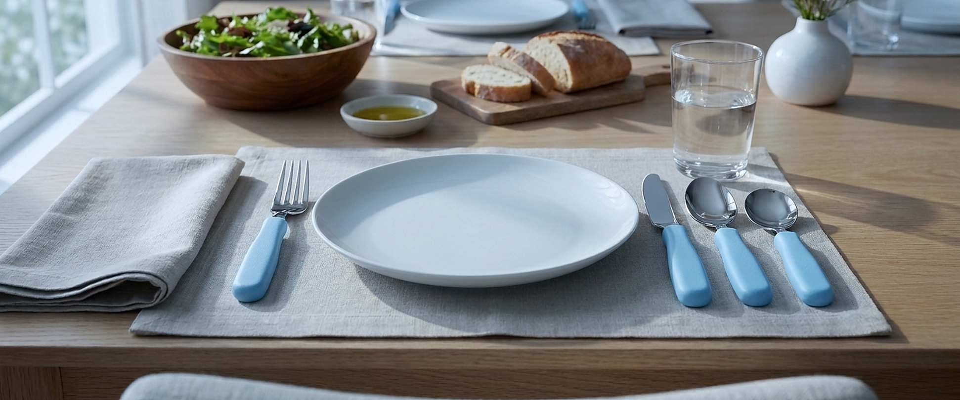 A dinner table set with chunky blue plastic-handled cutlery
